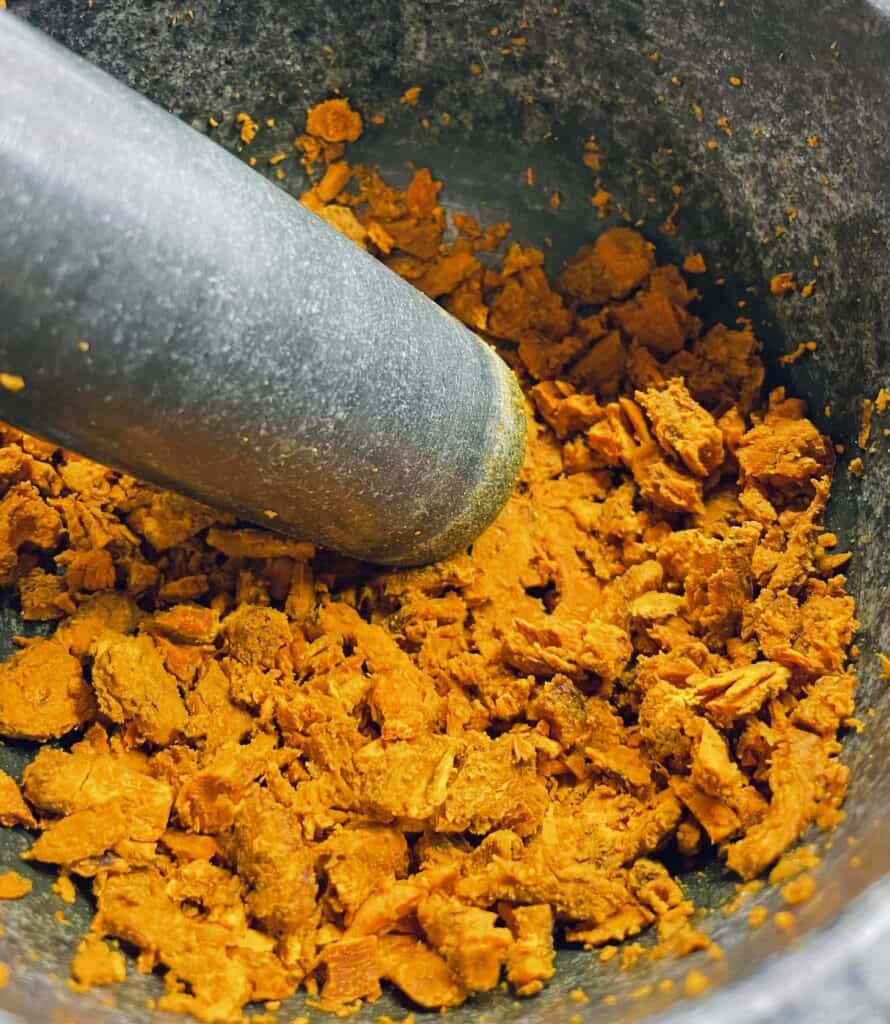 Lightly Pounded Whole Dried Turmeric in Mortar.