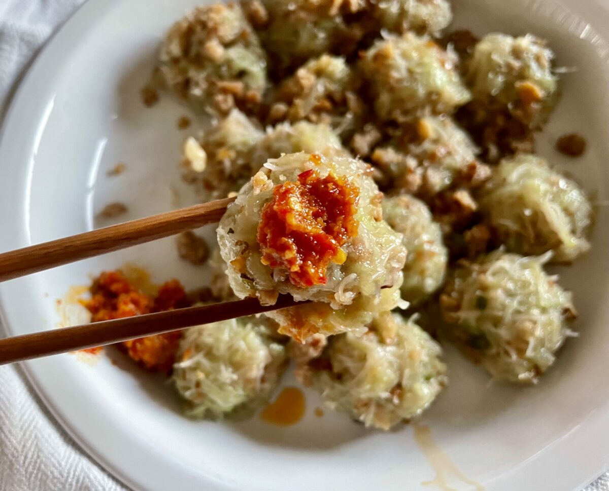 Chinese red chili and garlic paste on niouk yen dumplings. One niouk yen dumpling being held by a chopstick.