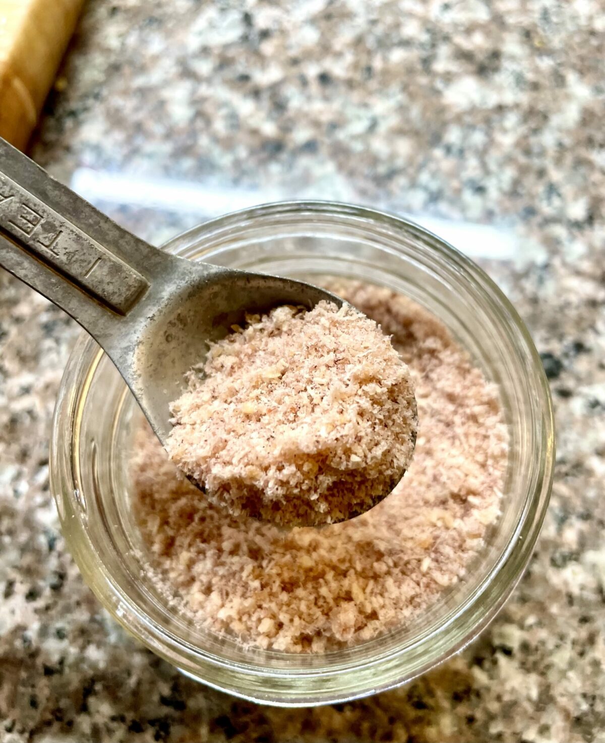 Dried squid powder in small mason jar and aluminum teaspoon.