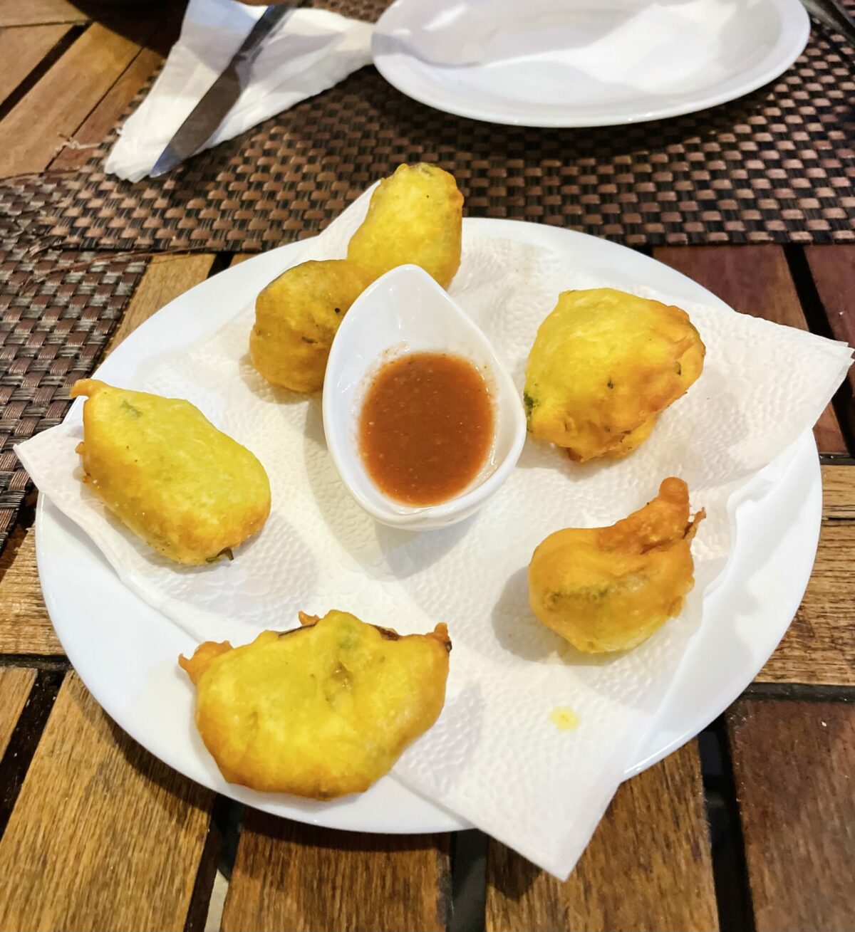 Gato de l'huile - Mauritian potato pakora on a white plate and napkin absorbing excess oil from cakes. Red chili sauce condiment for dipping. At Escale Créole Restaurant in Moka.