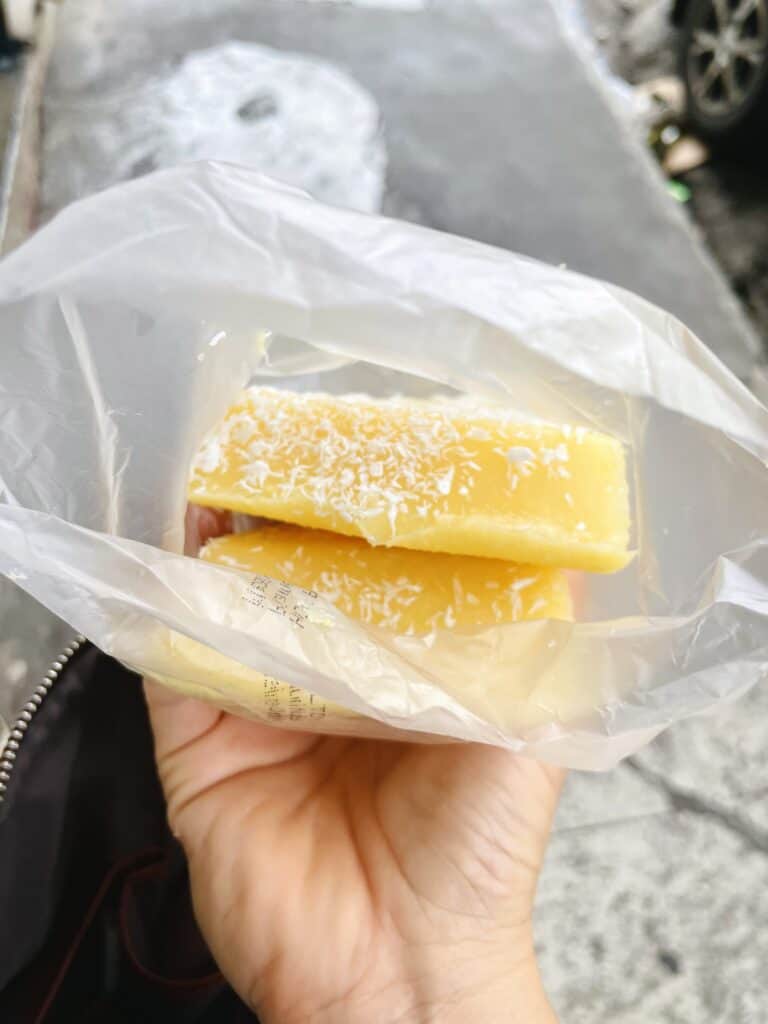 Corn pudding topped with shredded coconut in plastic bag.