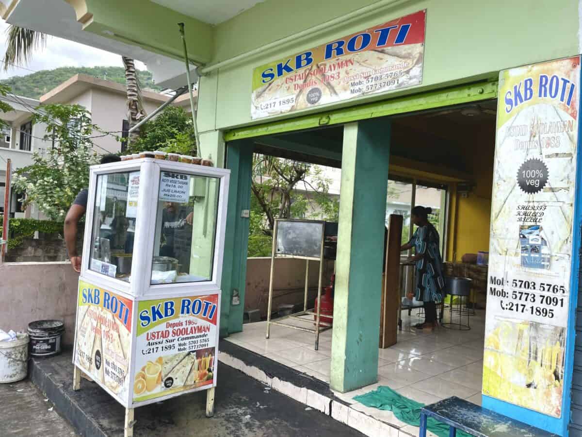 Mauritian vegetarian roti street food- SKB Roti vendor Port Louis with lady rolling roti inside.