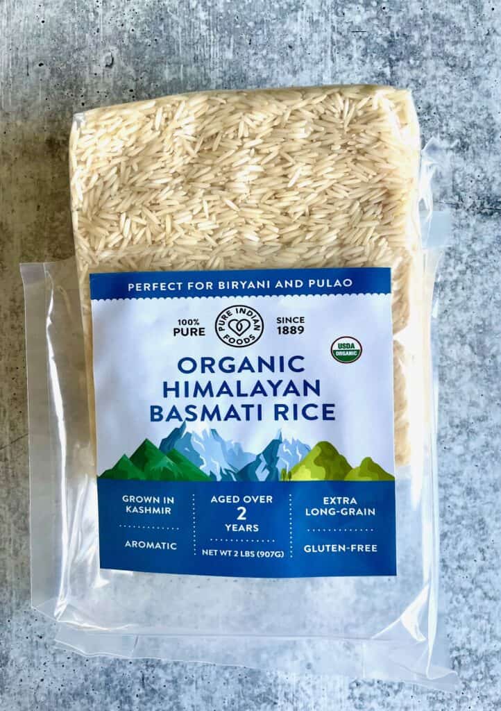 Pure Indian Foods basmati rice, opened outside package and intact vacuumed sealed package inside partly sticking out.