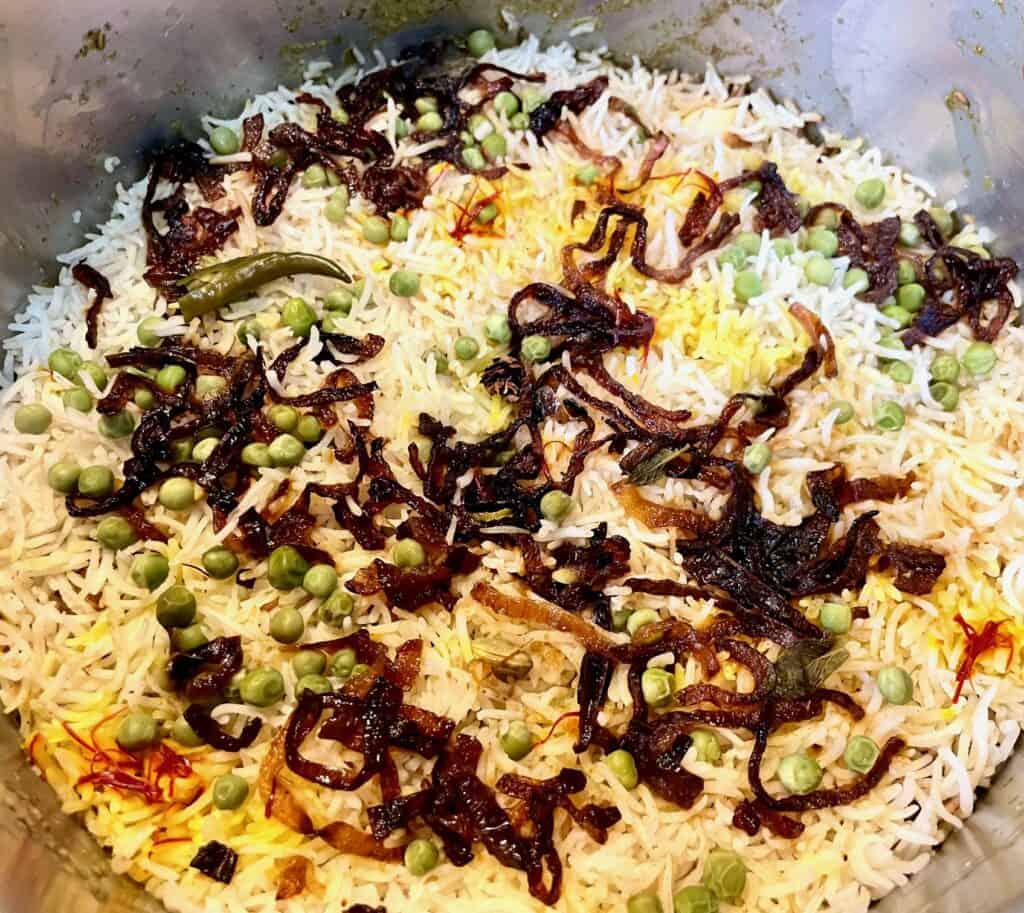 Top of chicken briani post cooking. Peas, saffrom and fried red onion on basmati rice.