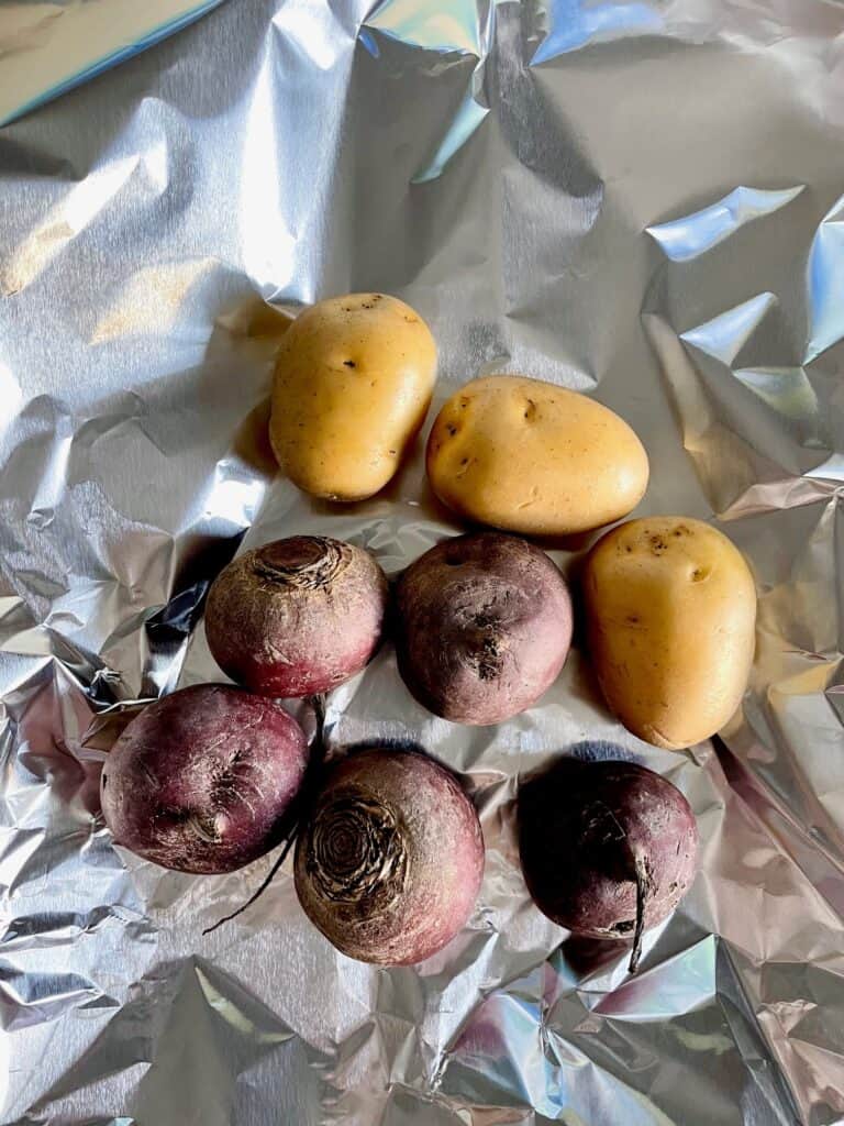Potatoes and beets on aluminum foil.