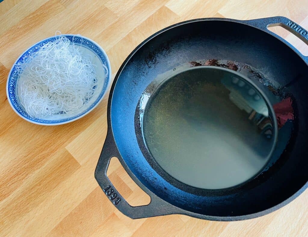 Rice vermicelli in Chinese plate and oil in Lodge cast iron pan.