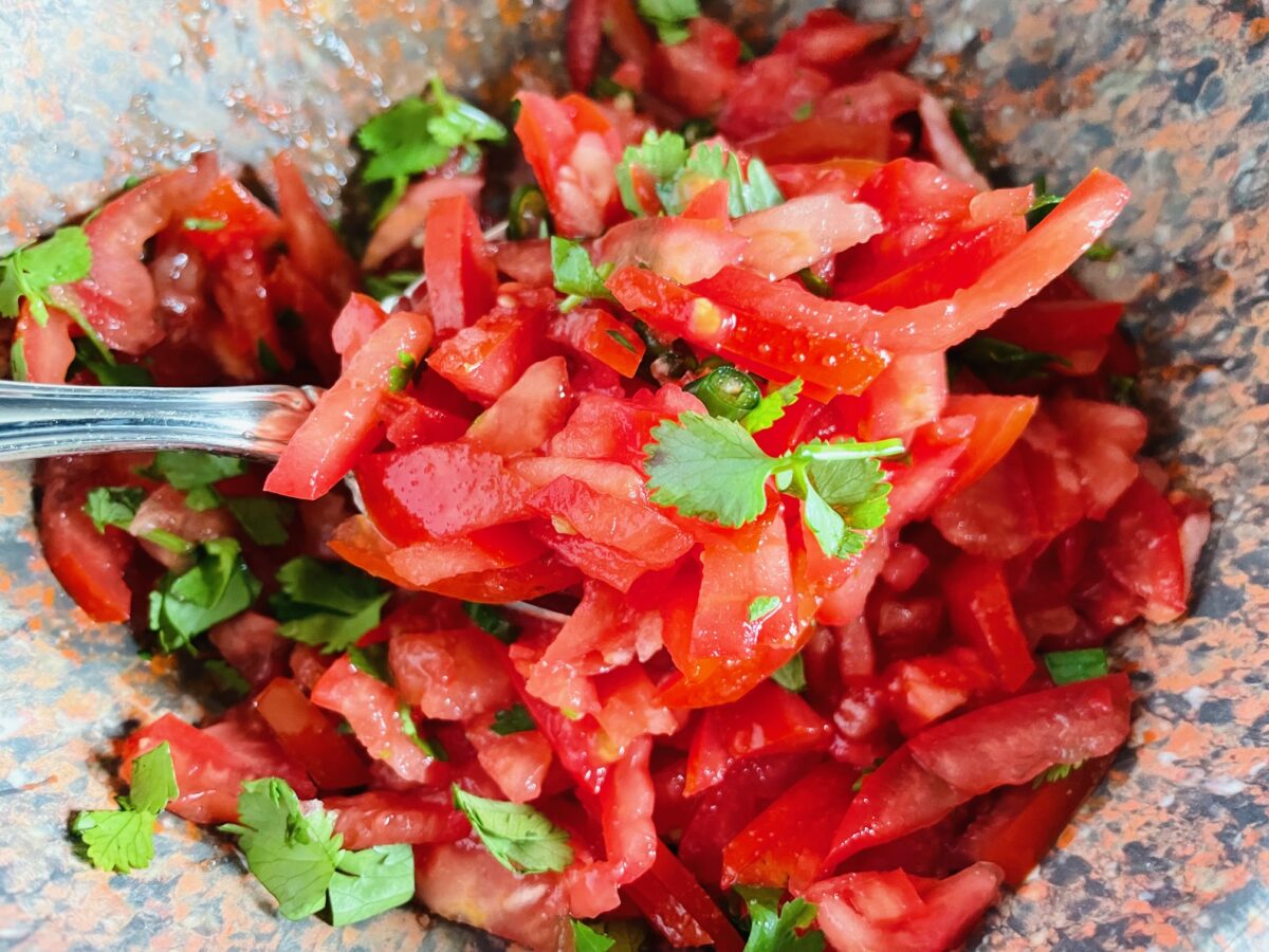 Thinly sliced tomatoes and coriander in bowl.