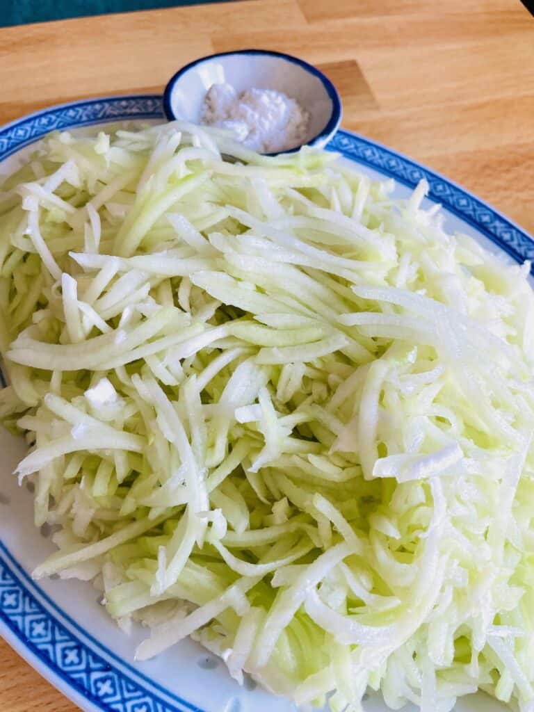 Shredded Chayote squash or Mauritian chouchou for niouk yen, salt in a small bowl in the background.